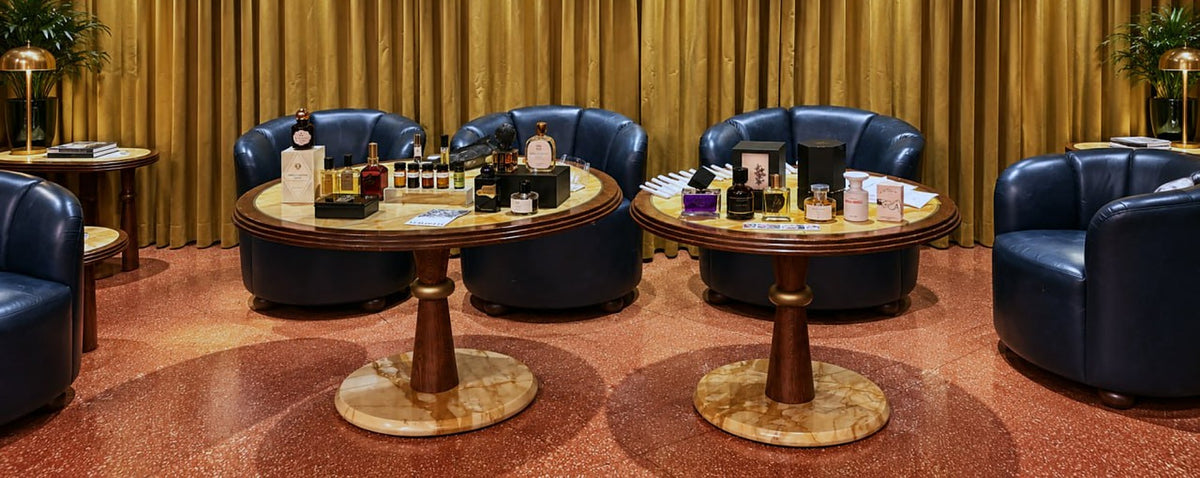 Two round tables with perfumes in front of a gold curtain at a Vetiveria event